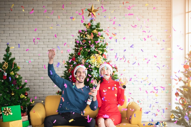 Um homem e uma mulher sentados no sofá comemorando o Natal