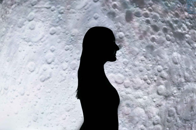 Silhueta de uma mulher em frente à Lua cheia