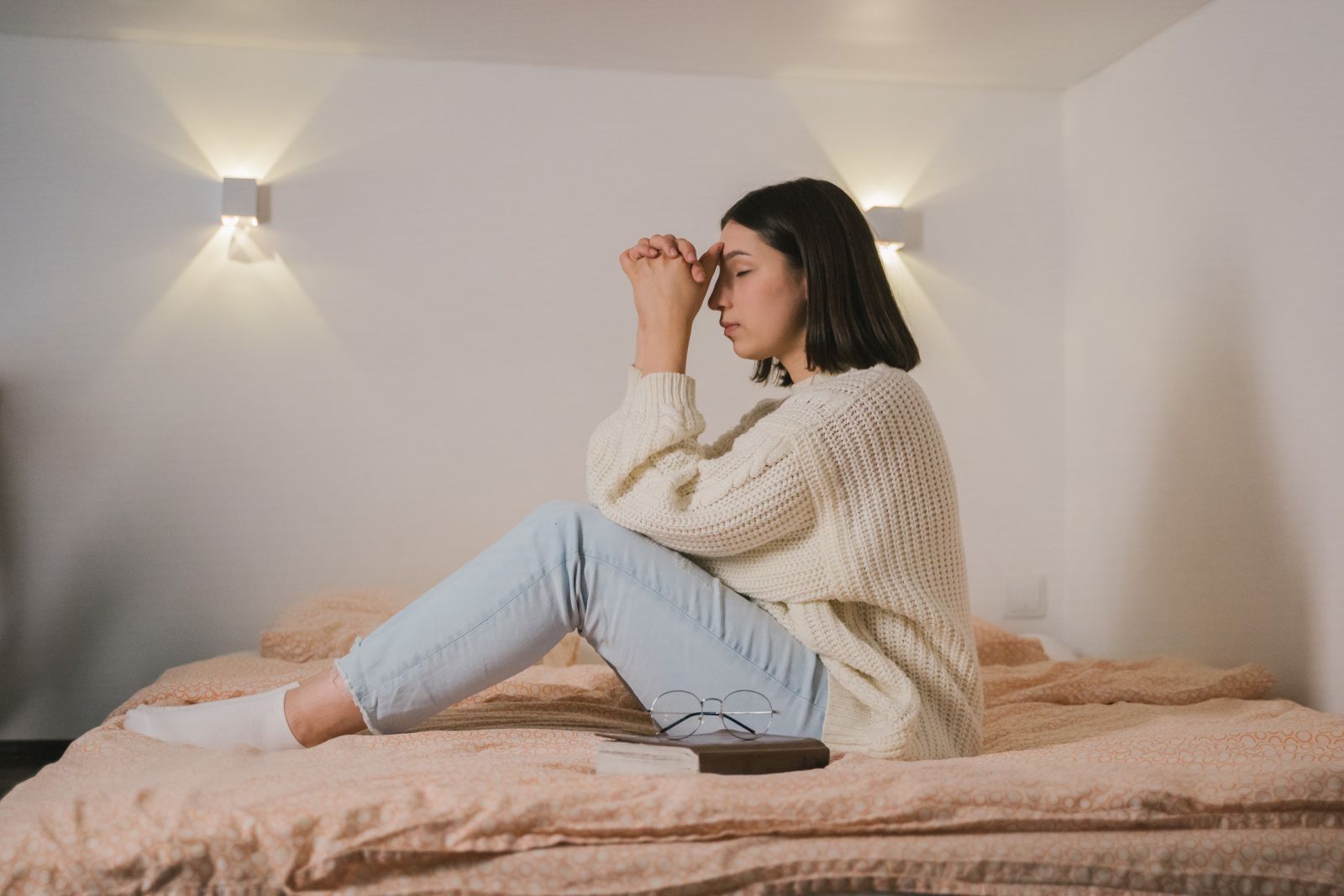 Mulher sentada na cama orando