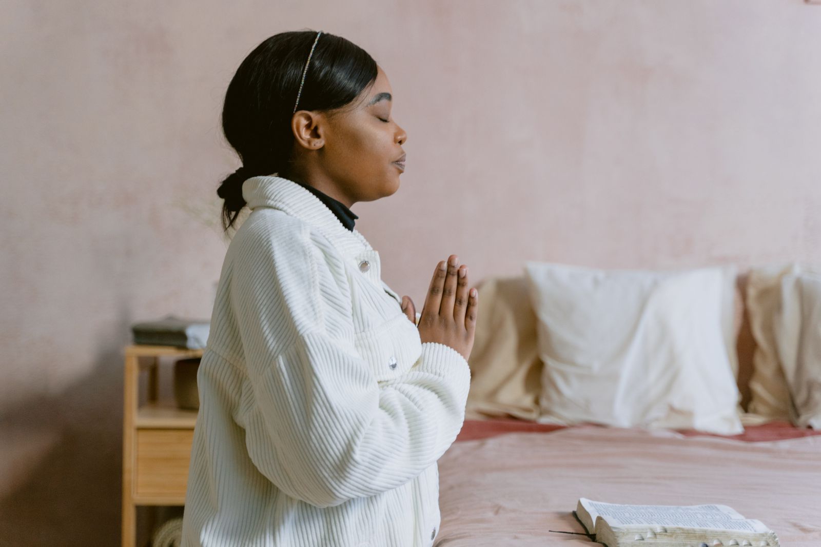 Mulher orando com bíblia em sua frente