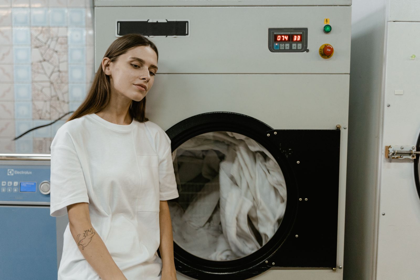 Mulher ao lado da máquina de lavar roupa