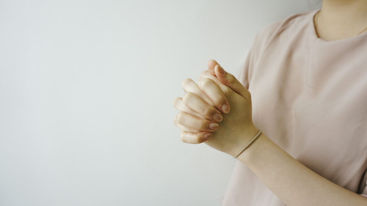 Pessoa com as mãos unidas em sinal de oração.