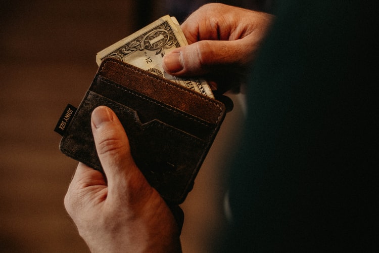 um homem segurando uma carteira e uma nota de dólar