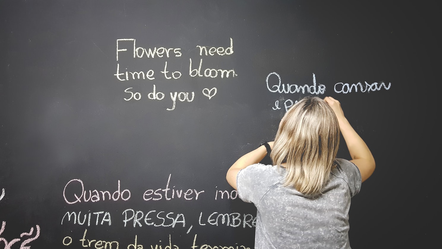 Mulher escrevendo em uma lousa de giz frases em inglês e português