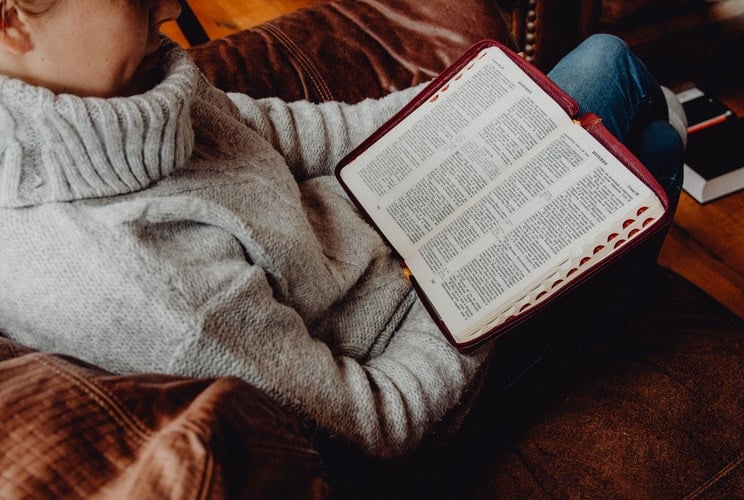 Imagem de uma senhora sentada com a bíblia na mão