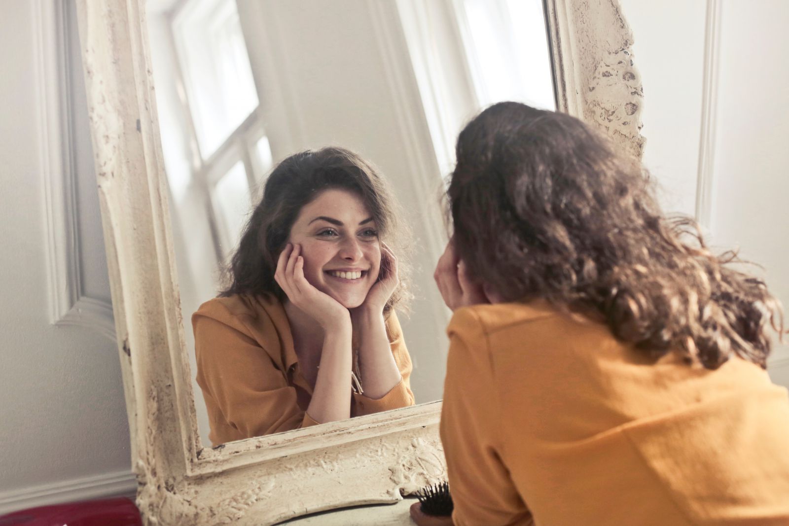 Mulher sorrindo em frente ao espelho