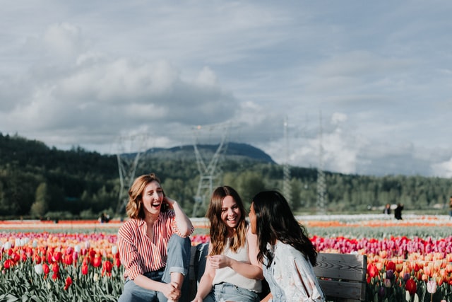 Mulheres rindo num campo de flores.