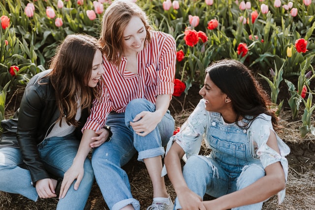 Mulheres brancas sentadas conversando num campo de tulipas.