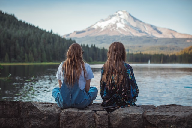 Duas meninas brancas de costas, observando paisagem.