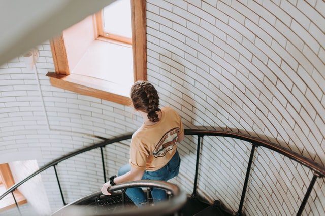 Samantha Gades / Unsplash Mulher descendo escada espiral.