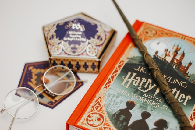 Livro de Harry Potter com varinha em cima e óculos ao lado.