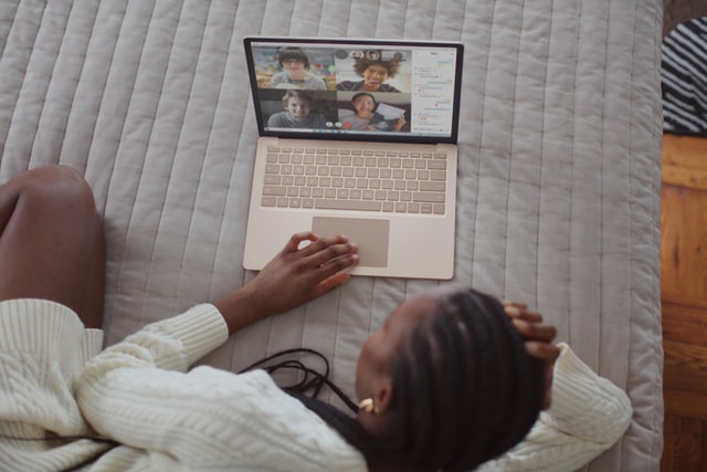 Mulher negra em frente à notebook em vídeo-chamada.