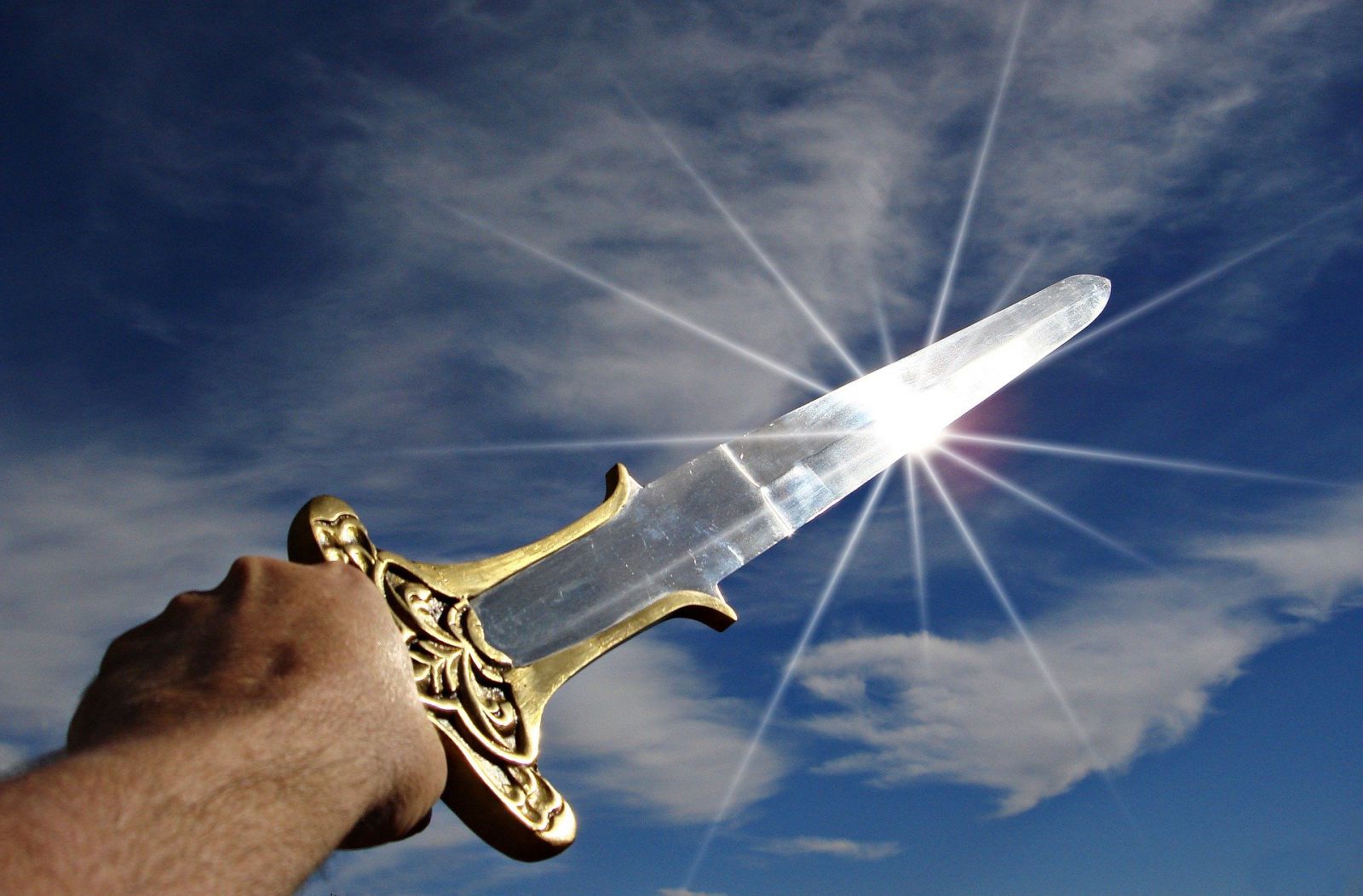 Uma mão segurando uma espada e apontada para o céu