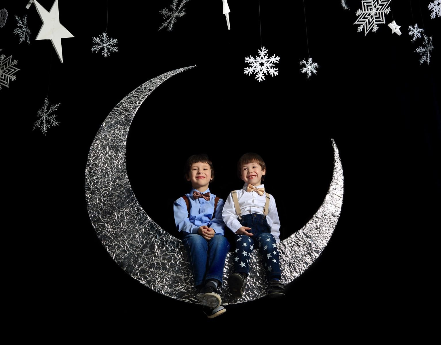 Dois meninos gêmeos pendurados em uma lua.