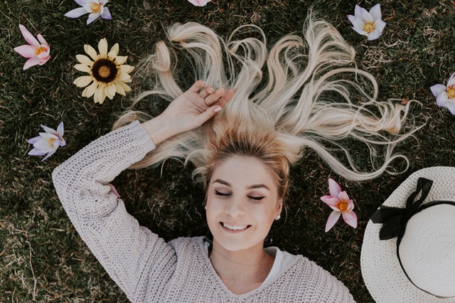 Mulher deitada no chão com flores nos cabelos espalhados no chão 