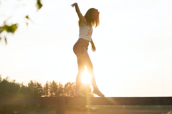 Mulher andando em viga de madeira se equilibrando