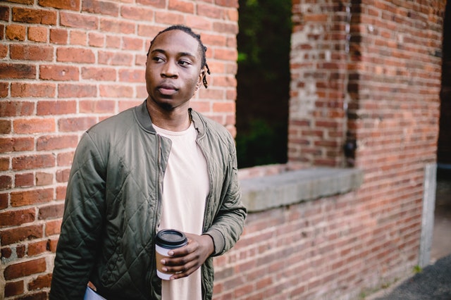 Foto de Ketut Subiyanto no Pexels Homem segurando um copo de café com a mão esquerda e olhando para o lado direito